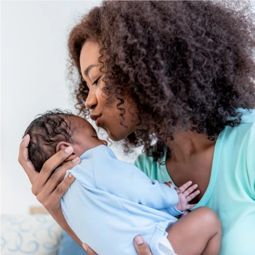 woman kissing newborn baby