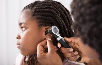 Doctor Using Otoscope Instrument To Check Girl's Ear In Hospital